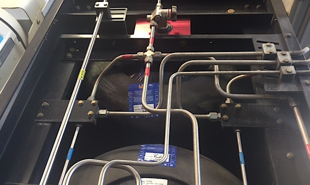An open CNG fueling system that is being inspected, displaying fuel lines, valves, and cylinders.